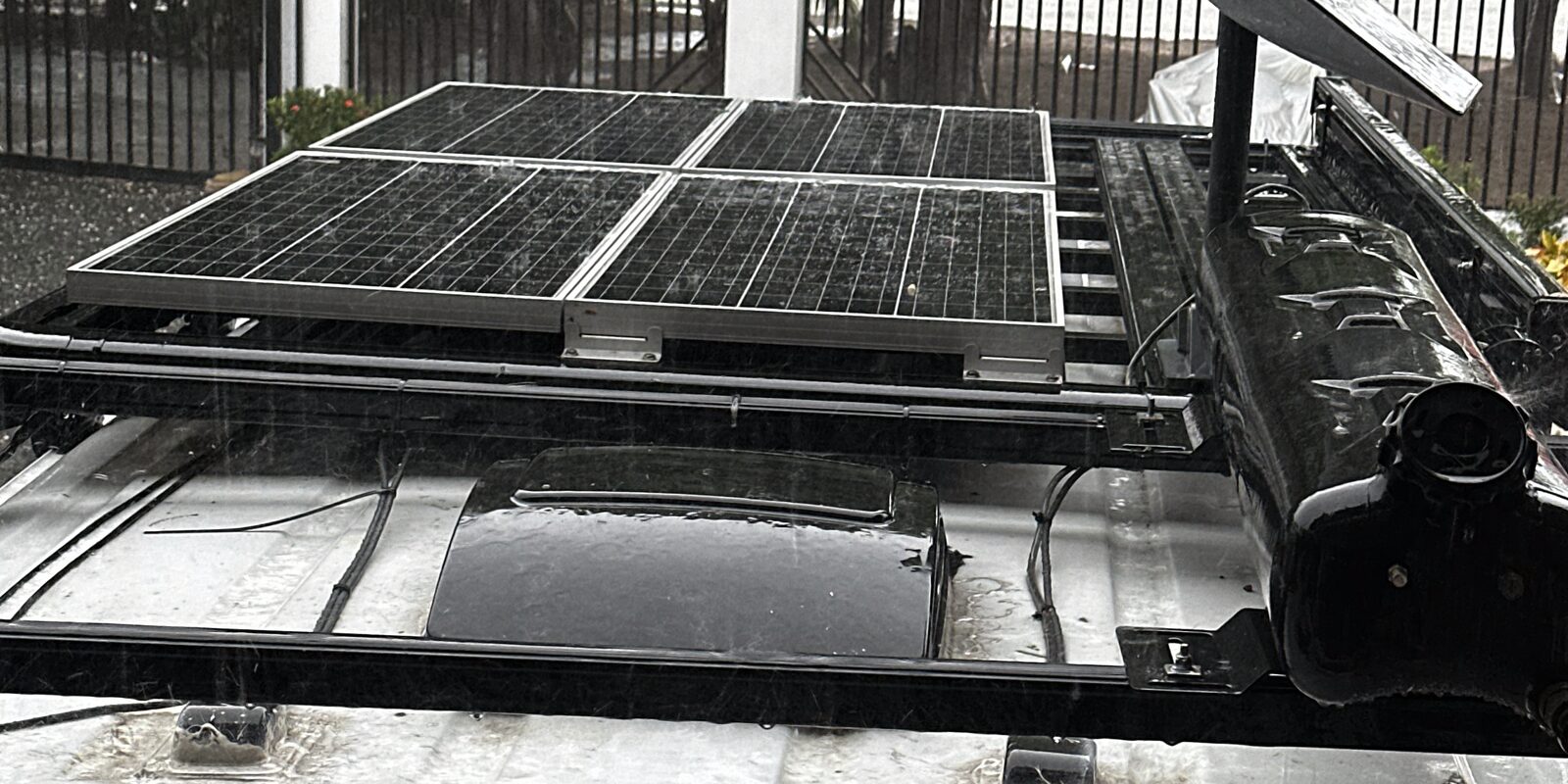 Four solar panels on a fabricated roof rack, with cable runs routed along the rails