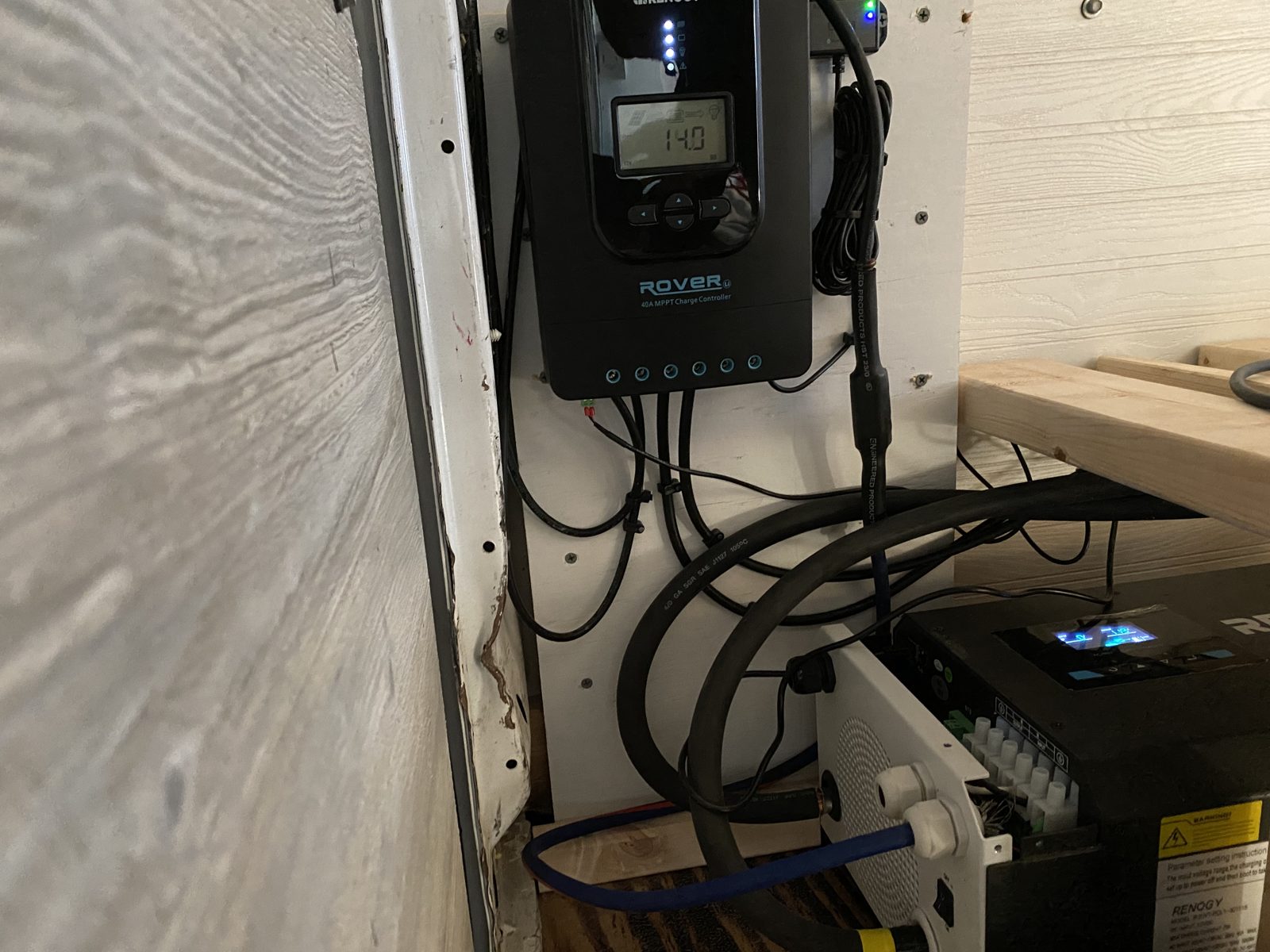 The MPPT charge controller and inverter mounted inside the van, with cable runs entering from below